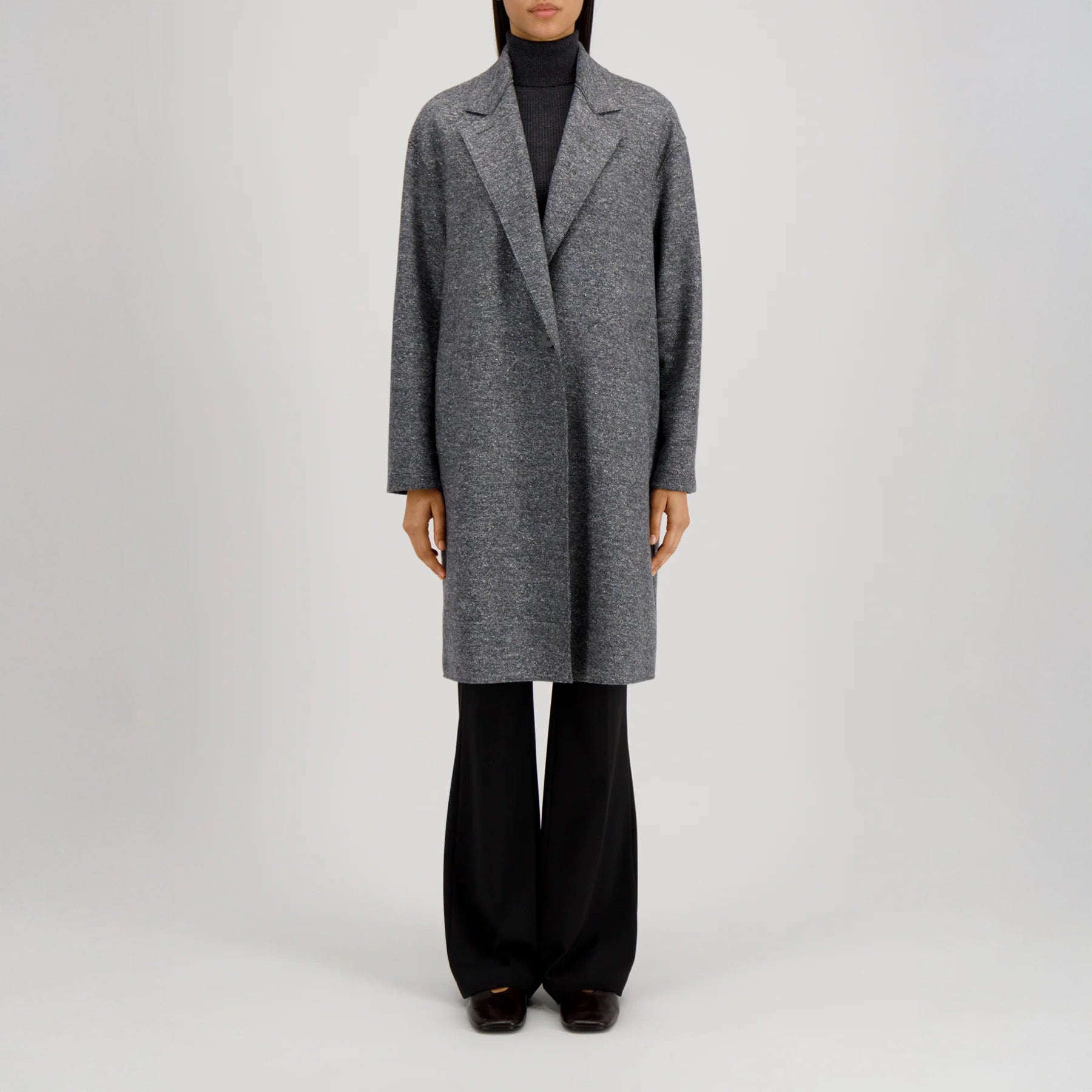 Model wearing the W Oversized Coat Donegal by Harris Wharf over a dark turtleneck and black pants, standing against a plain light background.