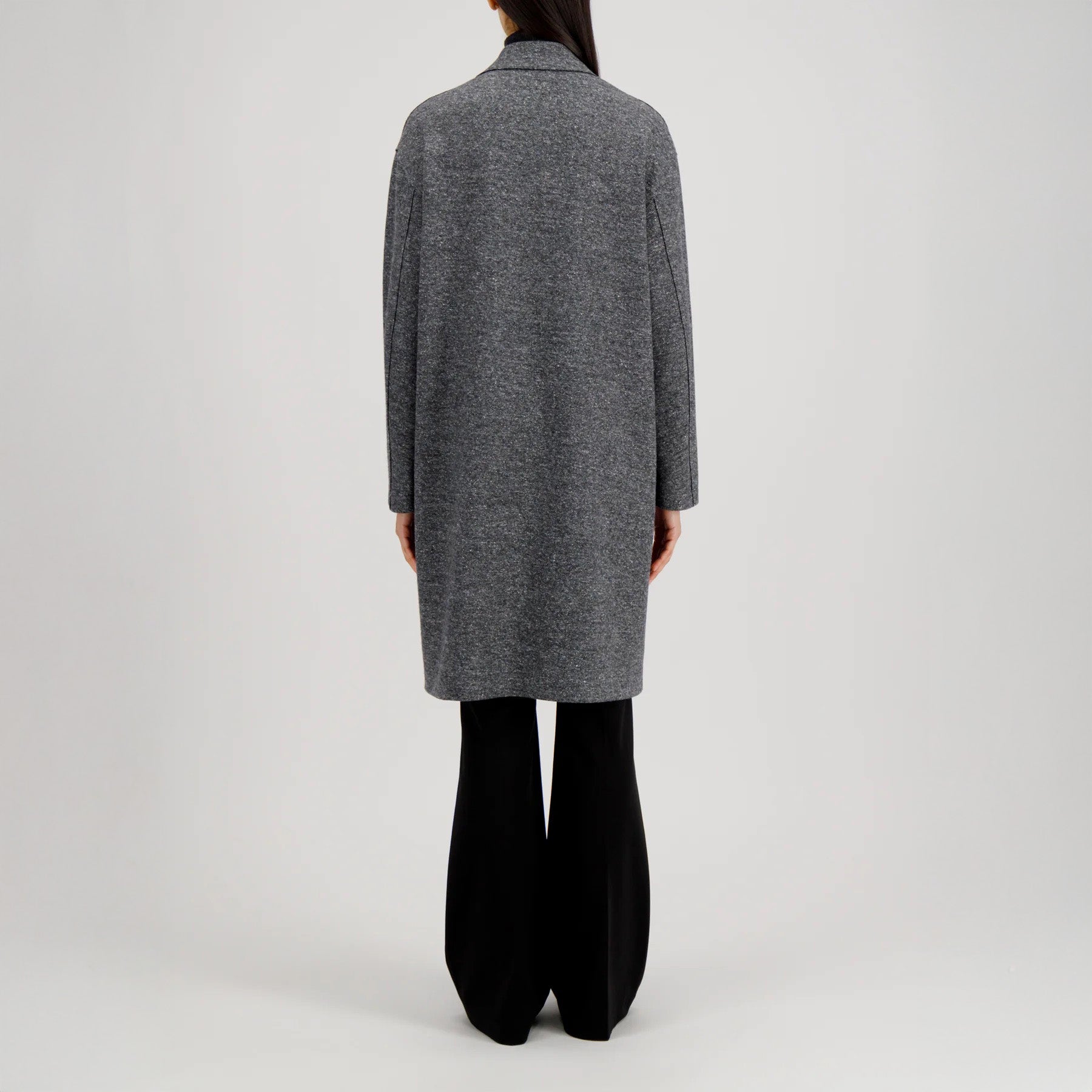 A person stands facing away, wearing the Harris Wharf W Oversized Coat Donegal over black pants against a plain light background.