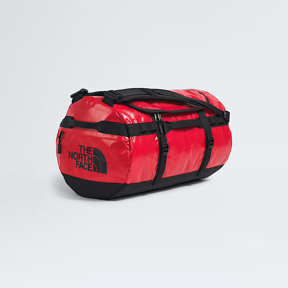 The North Face Base Camp Duffel in TNF Red, shown on a light gray background, features black straps and logo—an ideal waterproof bag for any adventure.