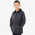A young boy stands against a white background, hands in the pockets of his Barbour Boys Liddesdale Quilted Jacket. The quilted design and needlecord collar give it charm, and it's perfectly tailored for kids.