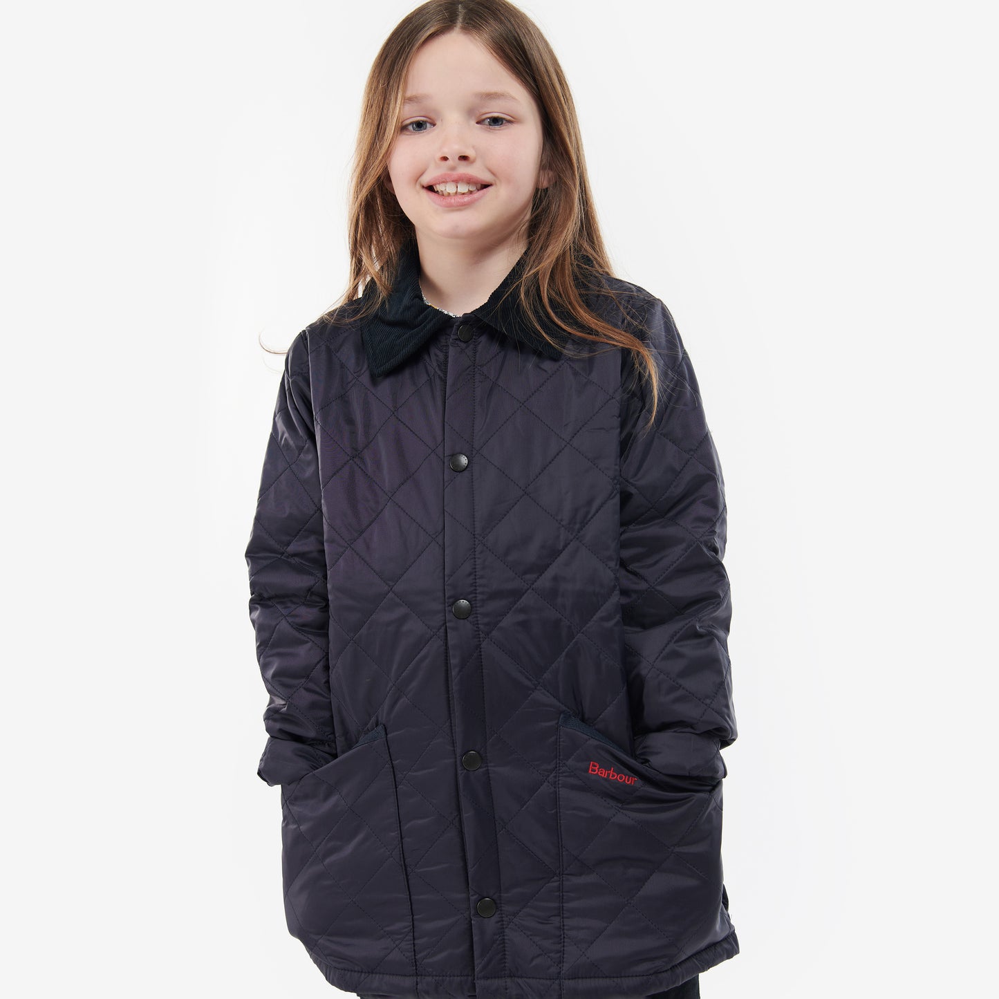 A child wearing the Barbour Boys Liddesdale Quilted Jacket, featuring a needlecord collar and pockets, smiles at the camera against a white background.