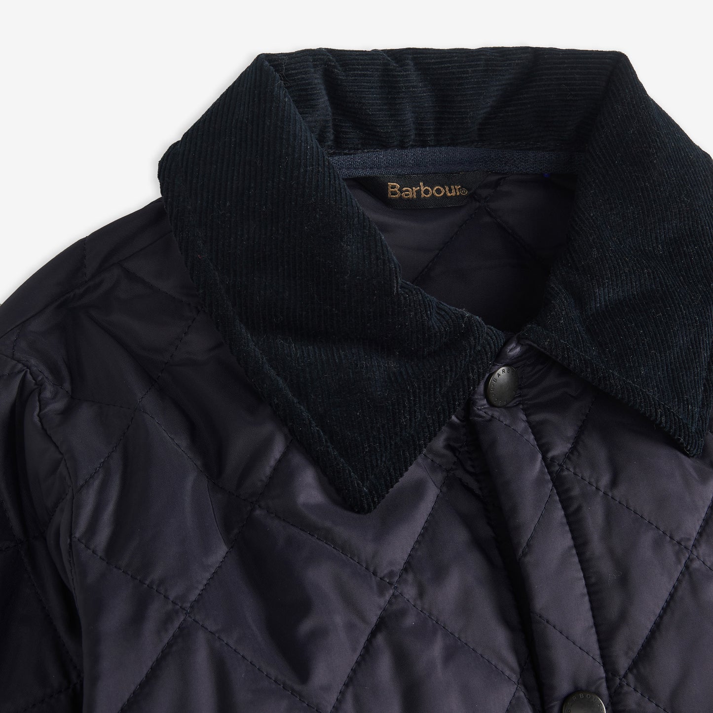 Close-up of the Boys Liddesdale Quilted Jacket, featuring a needlecord collar. The dark jacket by Barbour showcases visible stitching and buttons, embodying the classic quilted silhouette.