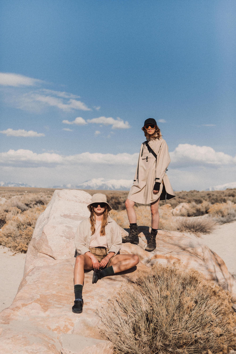 two models wearing beige shorts and tops on a rock