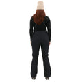 A person in black skiing attire and a beige beanie faces away, showcasing the sleek design of Halfdays' Emma Pant, highlighting the back of their outfit.