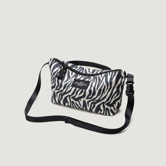 A Fannypack Crossbody bag with a black adjustable strap and logo on a plain grey background.