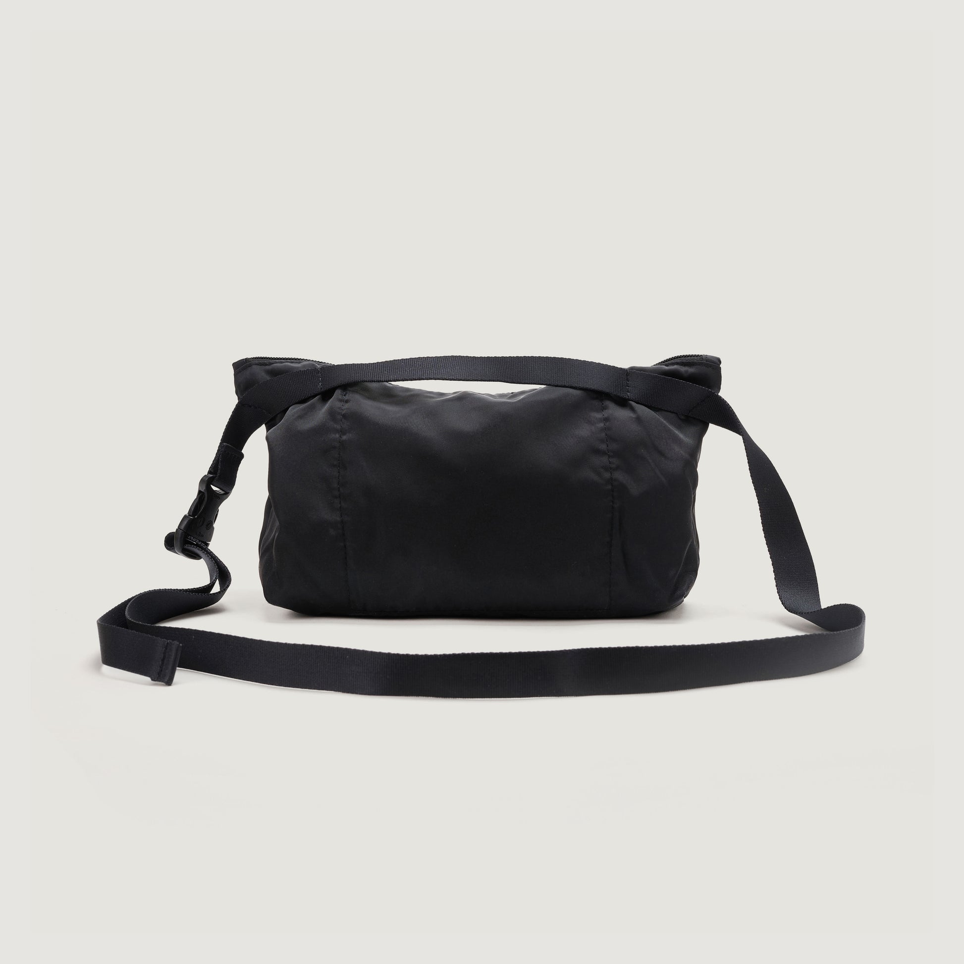 The Bags in Progress Fannypack Crossbody is a black bag made from water-repellent, recycled polyester with an adjustable shoulder strap, shown against a plain white background.