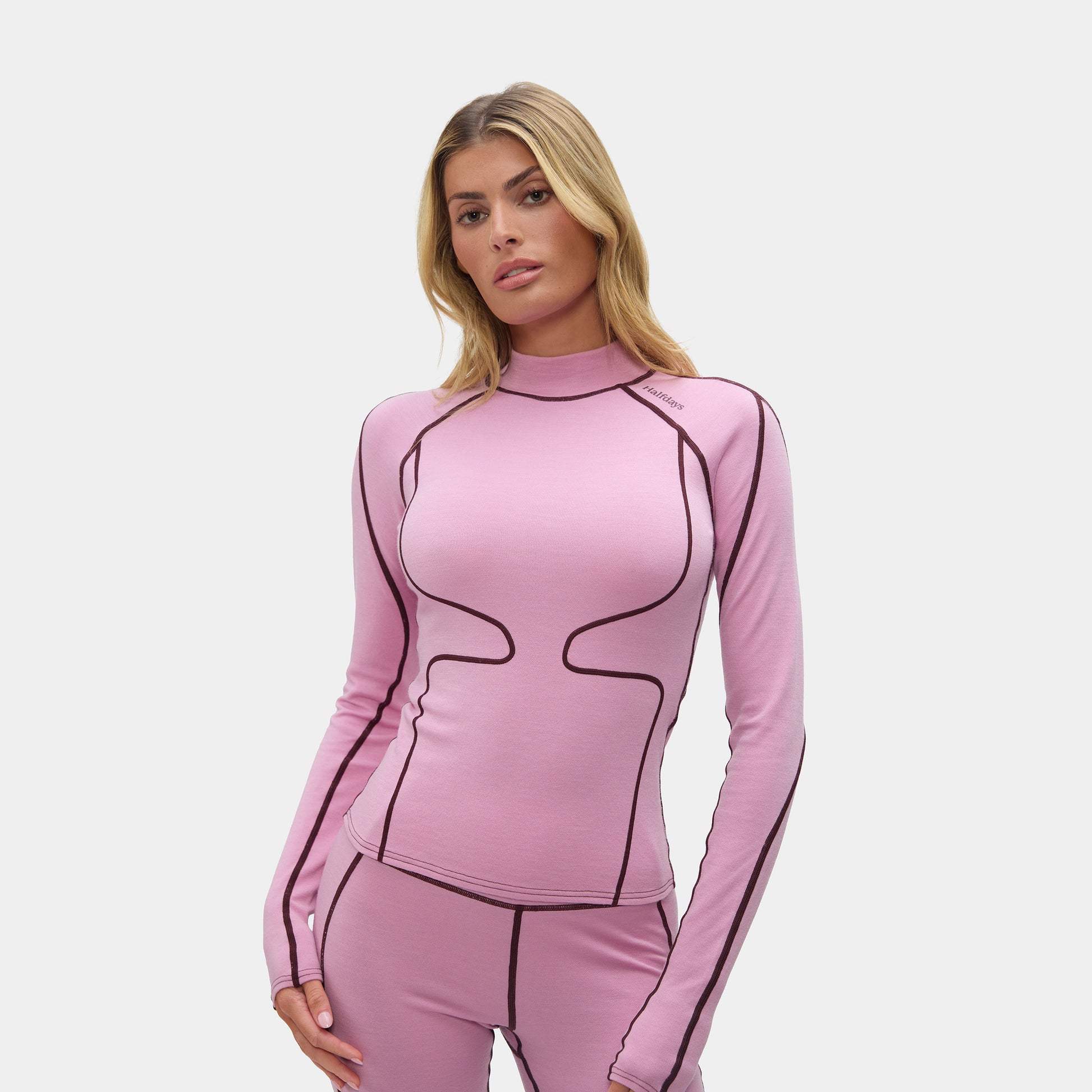 Woman wearing a pink long-sleeve top and pants with black accents on a white background