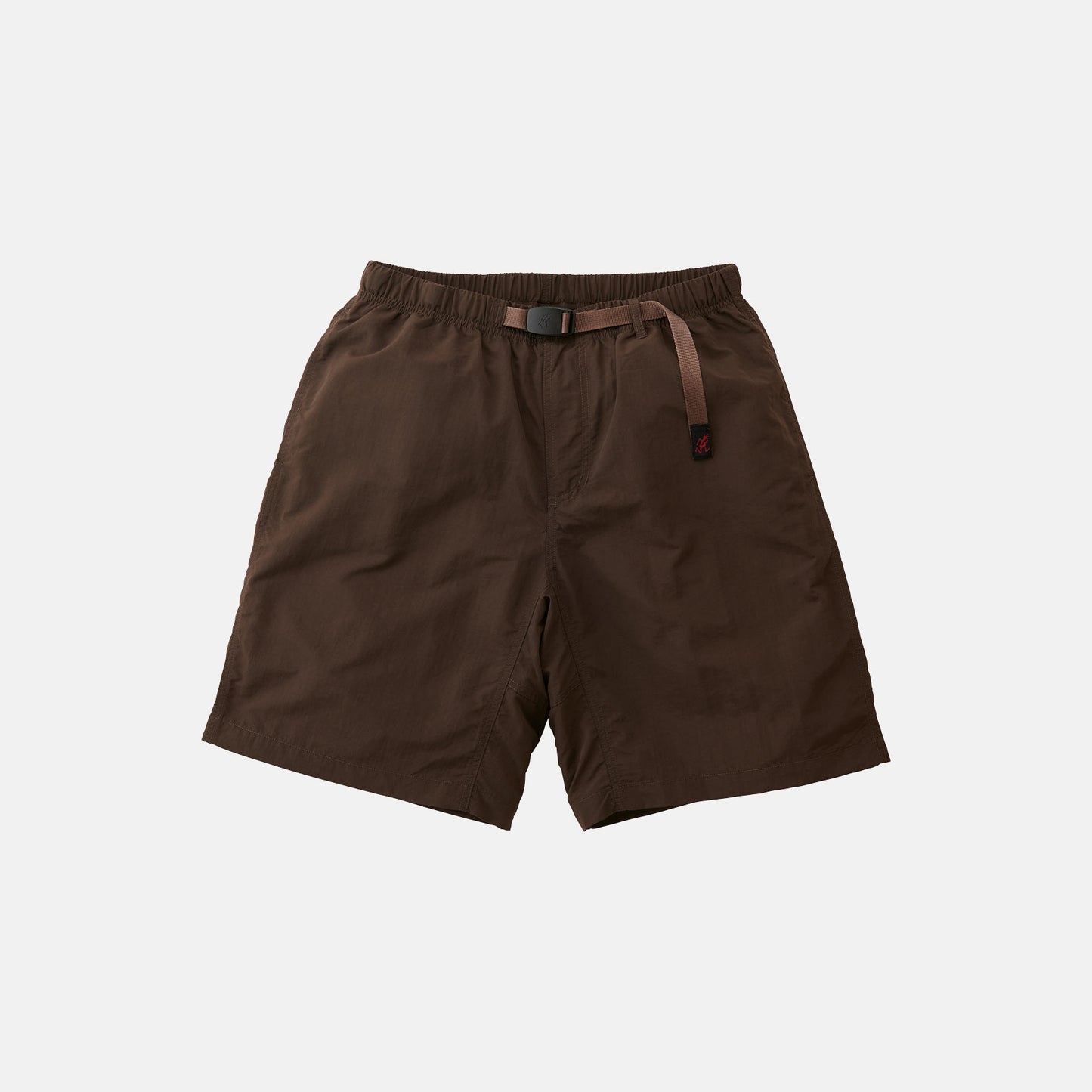 The Gramicci Nylon Loose Short, in brown, features knee-length nylon fabric, an elastic waistband with an integrated adjustable belt, and offers wind-resistant and water-repellent protection. Shown on a plain white background.