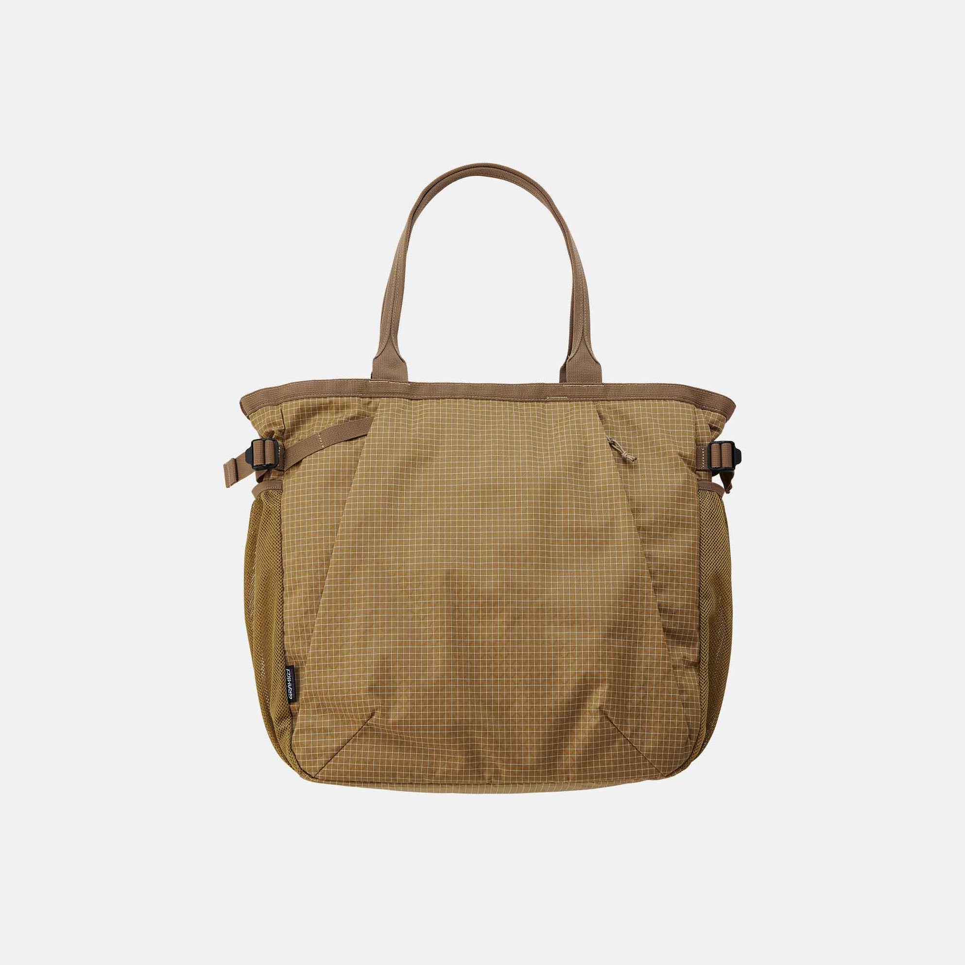 The Gramicci Riptstop Tote Bag features a beige checkered pattern, dual handles, and side buckles, set against a plain white background.