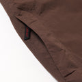 Close-up of Gramicci Nylon Runners in brown, highlighting a side seam zipper pocket with a black and red Gramicci tag stitched into the seam.