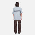A person stands facing away from the camera against a plain white background, wearing Gramicci Nylon Runners.