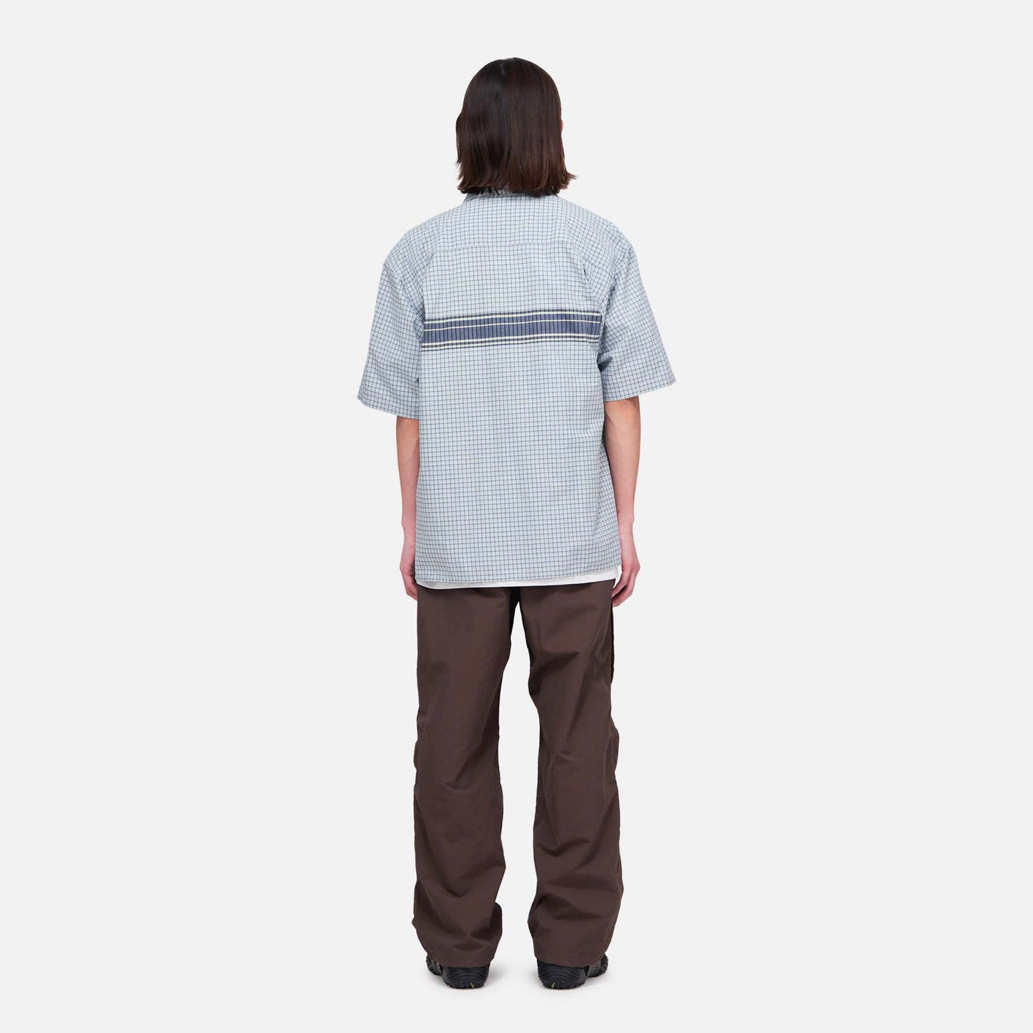 A person stands facing away from the camera against a plain white background, wearing Gramicci Nylon Runners.