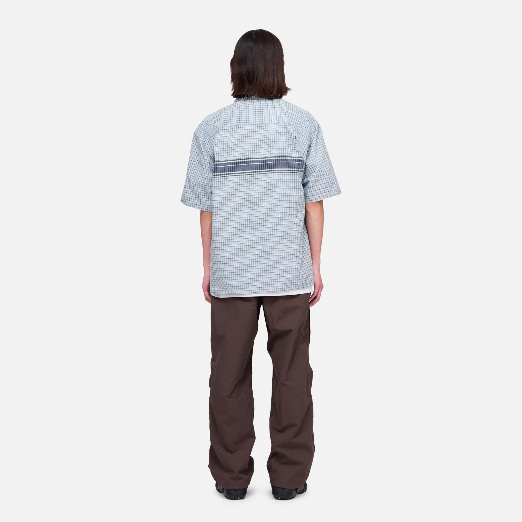 A person stands facing away from the camera against a plain white background, wearing Gramicci Nylon Runners.