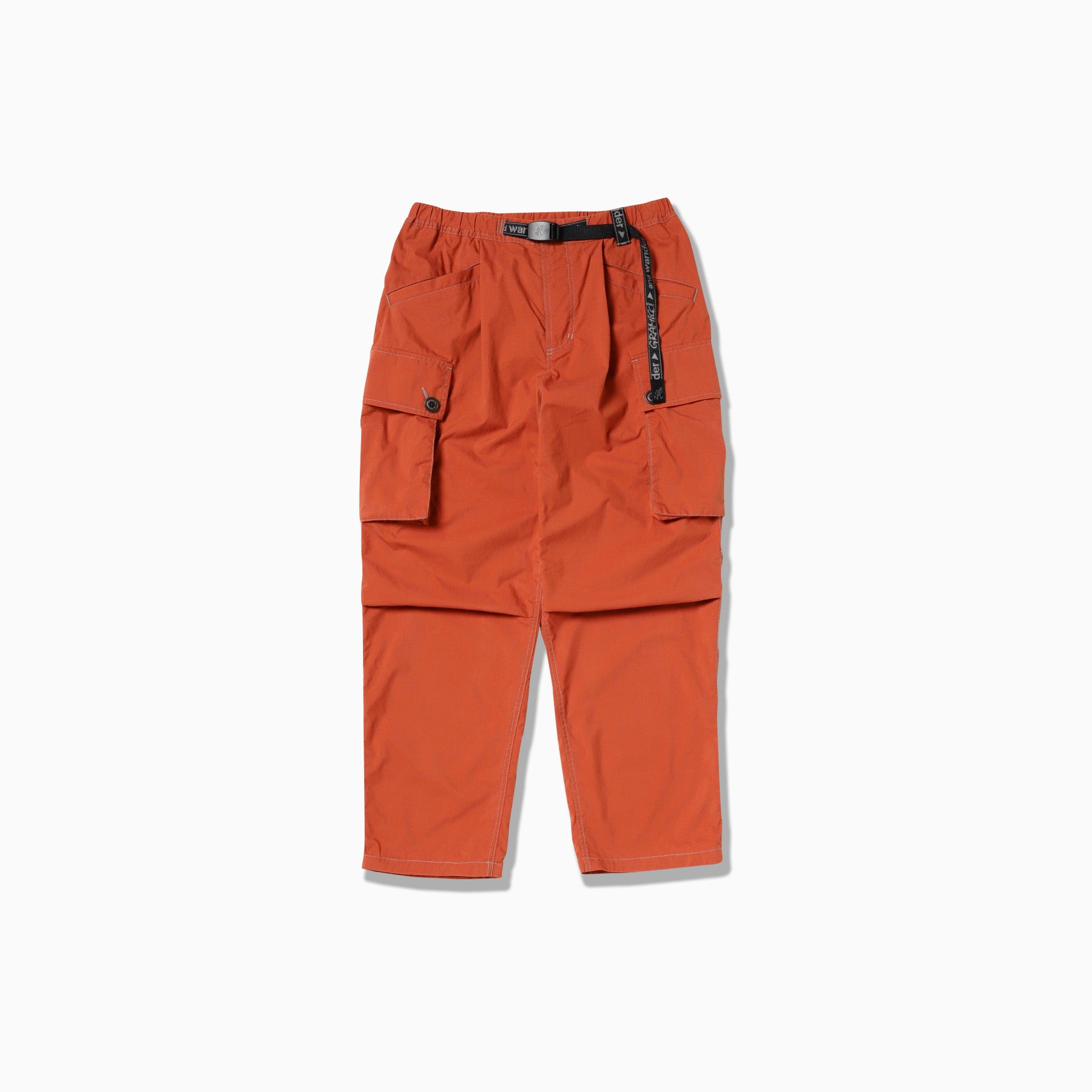 The Gramicci x And Wander Military Wide Pant, featuring orange cargo style with two large pockets, black adjustable belt, and button details on each pocket, is displayed flat on a white background.