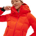 A person wearing the Georgie Puffer Jacket by Halfdays in bright red adjusts the collar with a slight smile, complete with a beanie.
