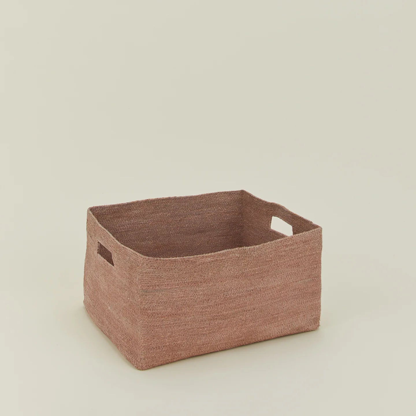 The Hawkins New York Essential Low Basket, a handwoven rectangular seagrass basket with two side handles, sits on a light surface—ideal for storing blankets and minimizing clutter against a plain background.
