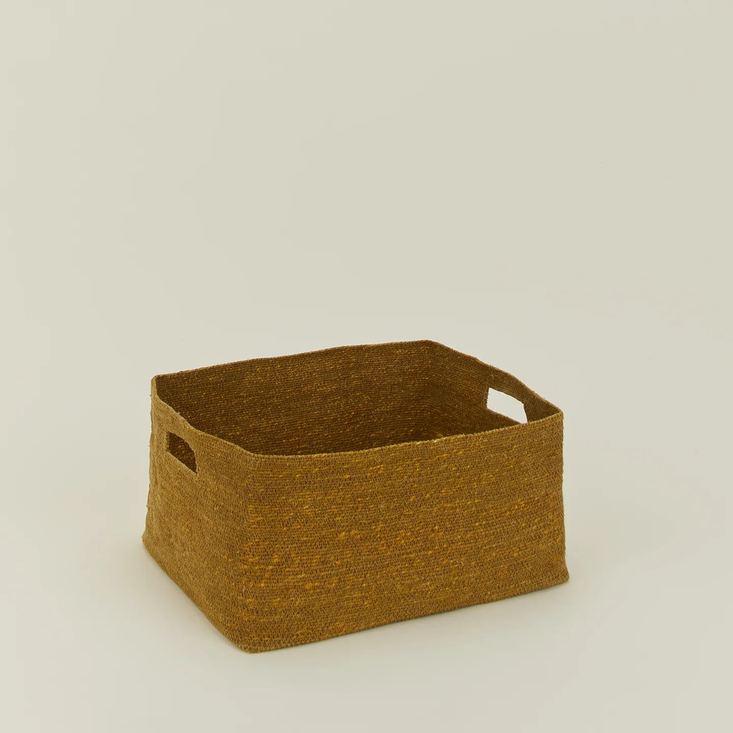 The Essential Low Basket by Hawkins New York is a rectangular handwoven seagrass basket with side handles, ideal for storing blankets and reducing clutter, shown on a plain light-colored surface.