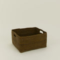 The Essential Low Basket by Hawkins New York, a handwoven seagrass piece with two side handles for blanket storage or clutter control, sits on a plain light background.