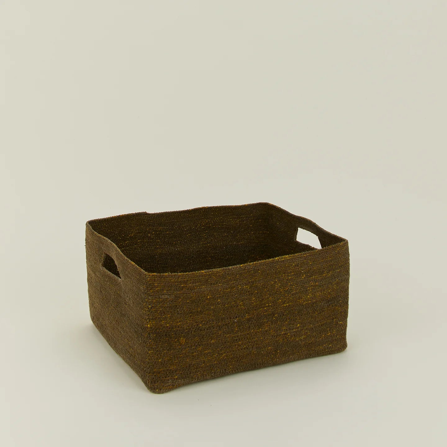 The Essential Low Basket by Hawkins New York, a handwoven seagrass piece with two side handles for blanket storage or clutter control, sits on a plain light background.