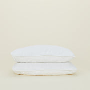 Two white Hawkins New York Simple Linen Euro Shams, made from soft European linen, are stacked on a plain, light-colored background.