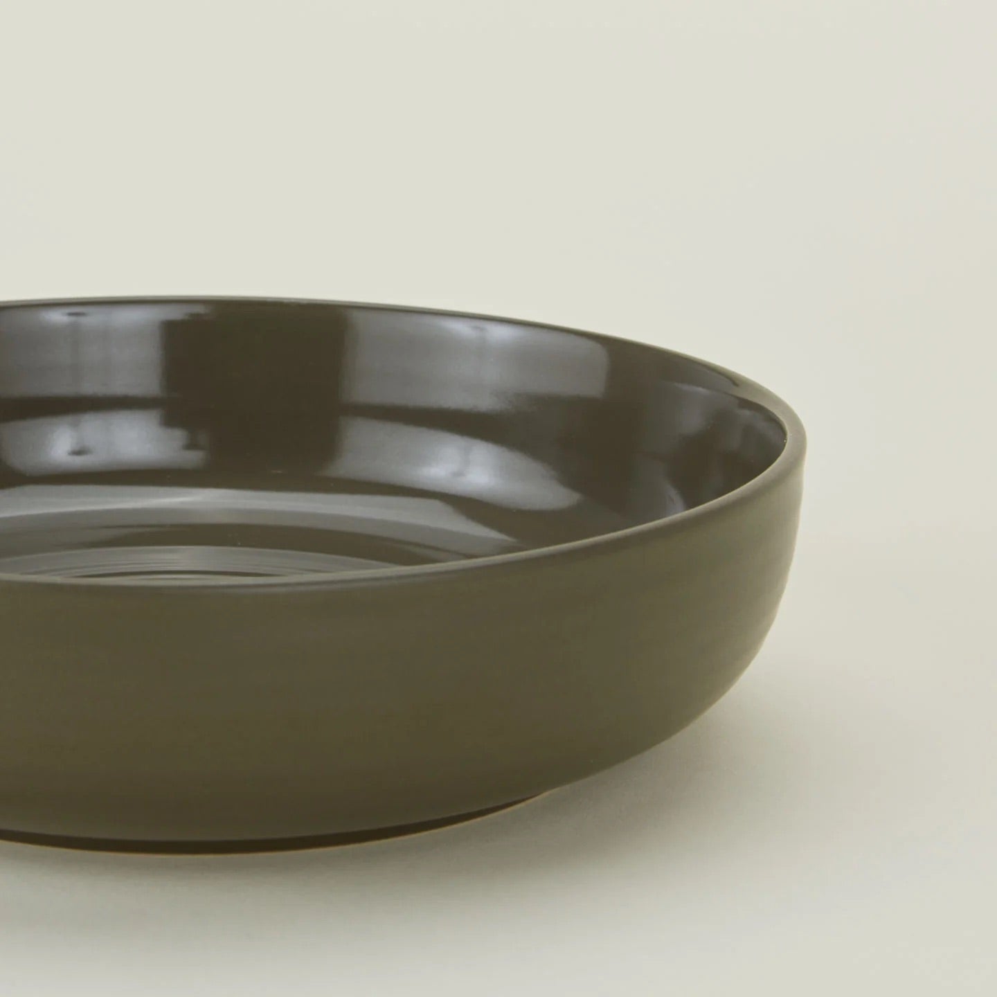 The Hawkins New York Essential Low Bowl (Set of 4), made of glossy dark green stoneware, is displayed against a plain light background.