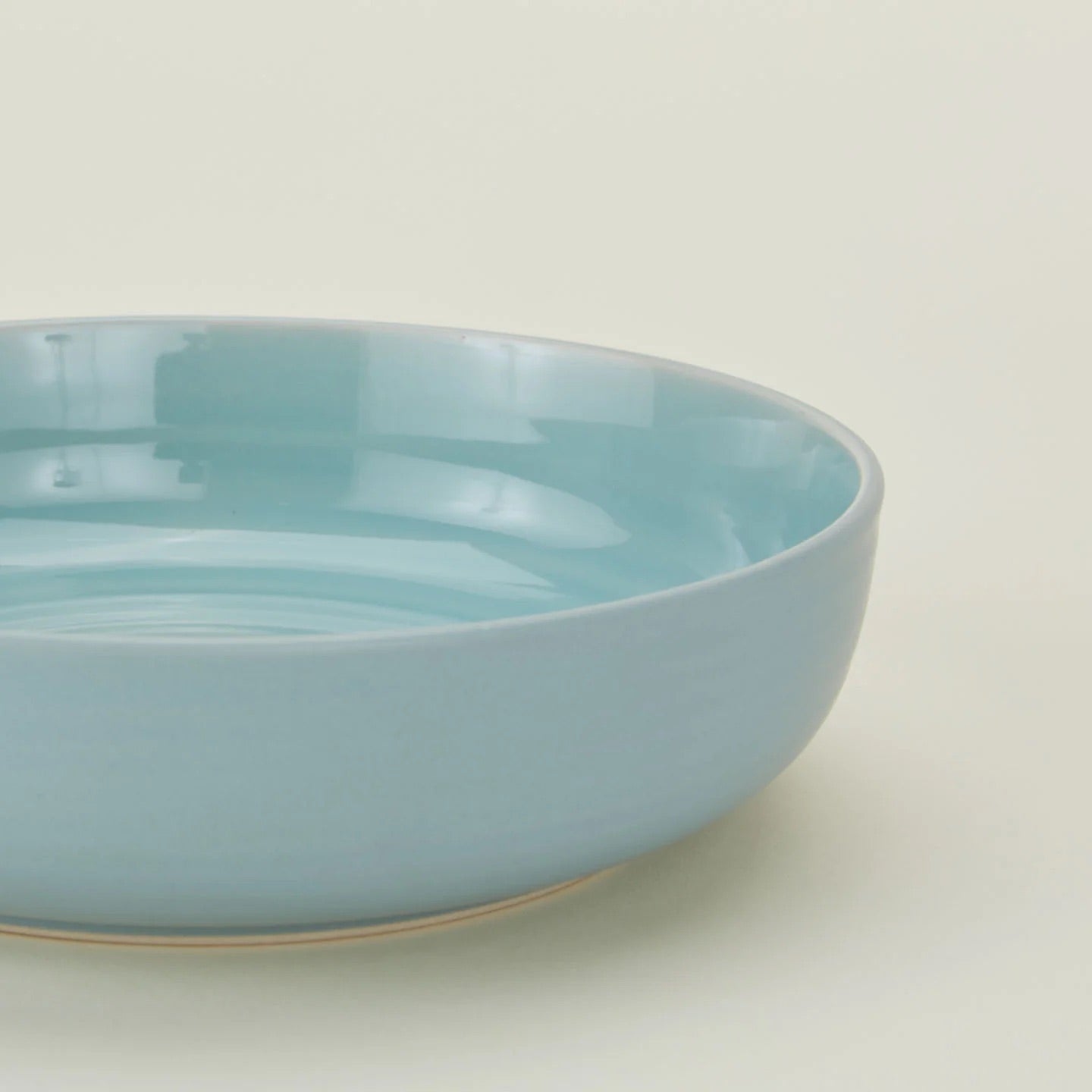 The Hawkins New York Essential Low Bowl (Set of 4), featuring a light blue glossy ceramic finish, from our stoneware dinnerware collection, is displayed on a plain off-white background.