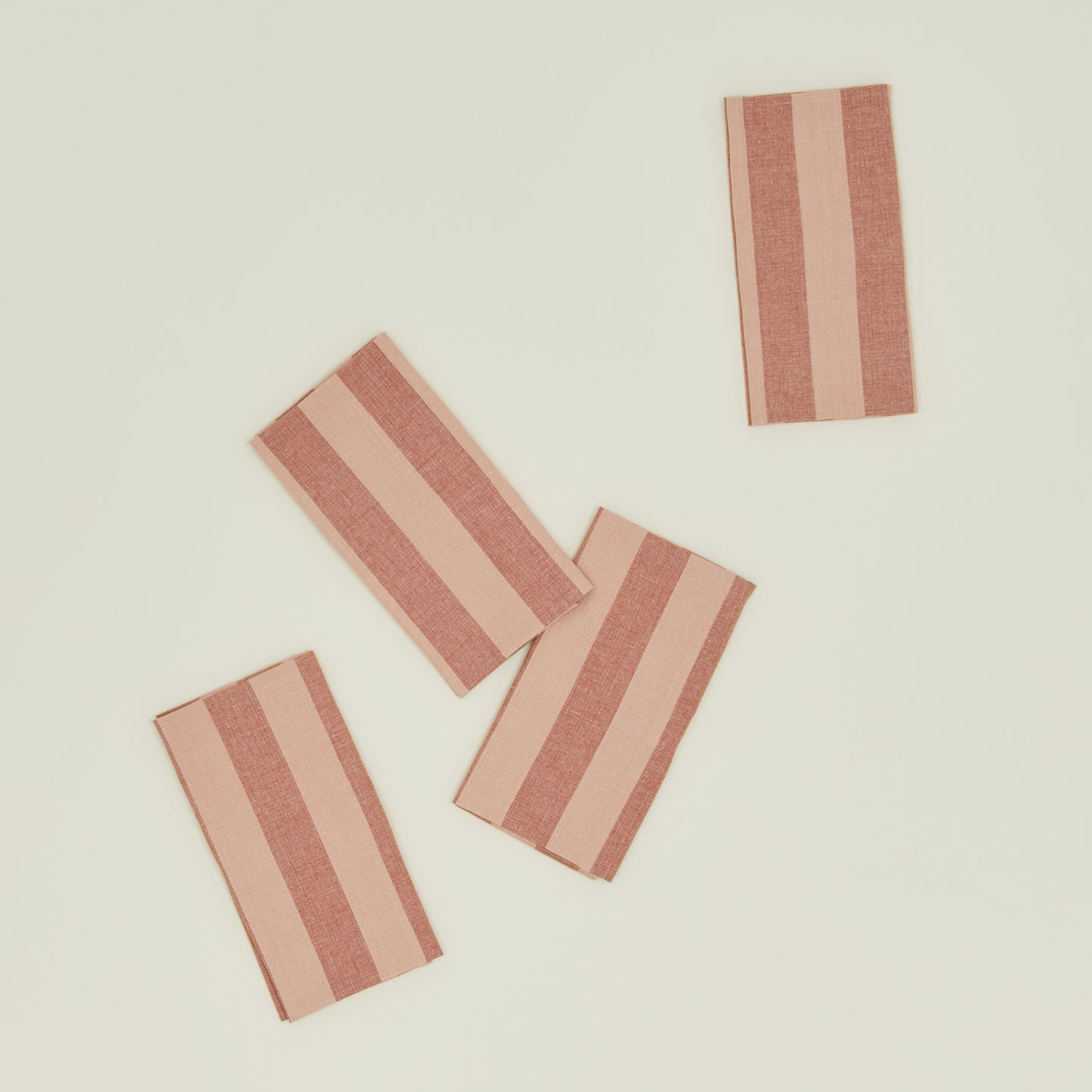 The Hawkins New York Essential Striped Placemats (Set of 4) feature an asymmetrical arrangement of rectangular, red-striped fabric against a light background, ideal for easy living.