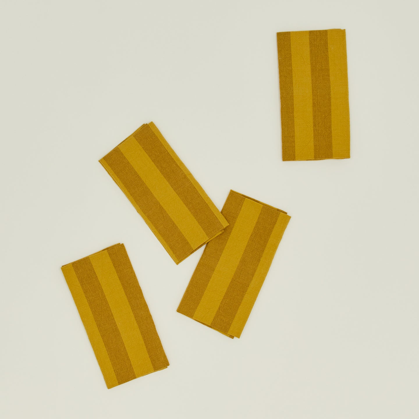 The Essential Striped Placemats (Set of 4) by Hawkins New York features beautifully arranged orange and brown stripes on a light green background, embodying the essence of easy living.