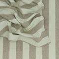 Close-up of crumpled Essential Striped Placemats (Set of 4) by Hawkins New York, featuring thick green and beige stripes against a matching striped backdrop, conveying an effortless sense of easy living.