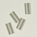 The Essential Collection by Hawkins New York offers a set of four rectangular placemats with alternating light gray and beige vertical stripes, perfectly complementing your home basics for a touch of easy living.