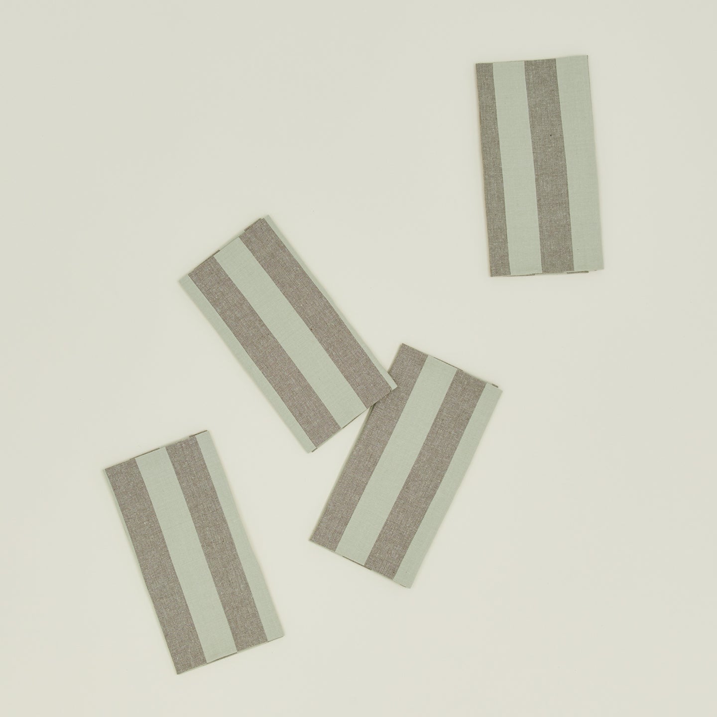 The Essential Collection by Hawkins New York offers a set of four rectangular placemats with alternating light gray and beige vertical stripes, perfectly complementing your home basics for a touch of easy living.