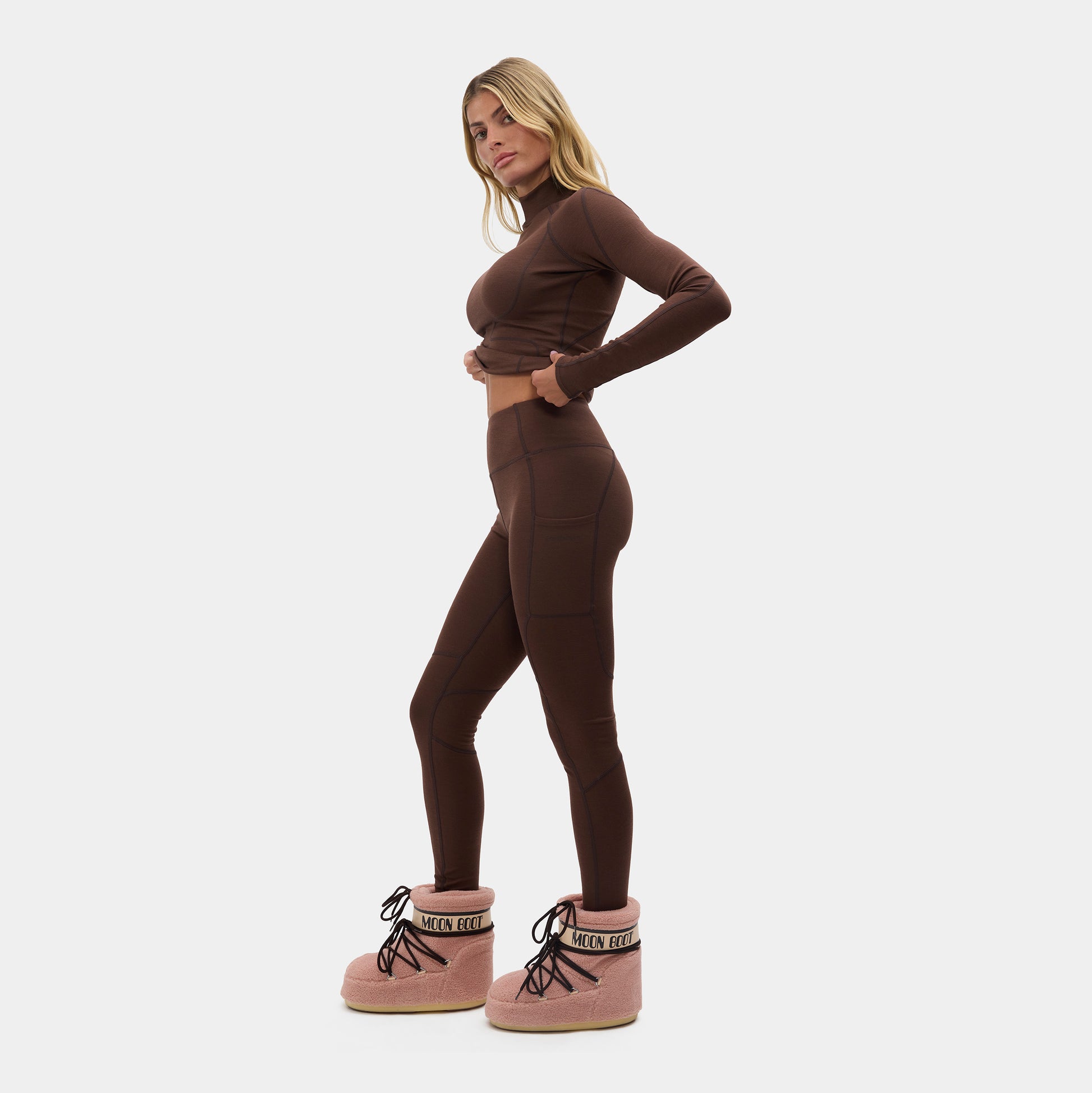 Woman wearing a brown outfit with pink boots on a white background