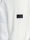 Close-up of the white textured fabric from the Hedge Men's Performance Hoodie, featuring a black "Nobis" patch on the sleeve and crafted with water-resistant technology.