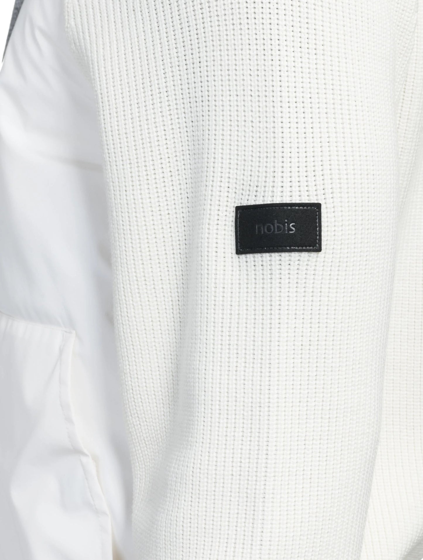 Close-up of the white textured fabric from the Hedge Men's Performance Hoodie, featuring a black "Nobis" patch on the sleeve and crafted with water-resistant technology.