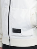 A close-up of a person wearing the Hedge Men's Performance Hoodie features a sleek white design with a black zipper and a bold black "Nobis" label on the front. This luxurious hoodie blends practicality and style with its water-resistant properties.