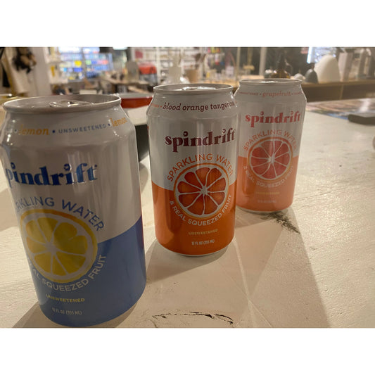 Three cans of Grapefruit Sparkling Water by Spindrift on a wooden table in a store.