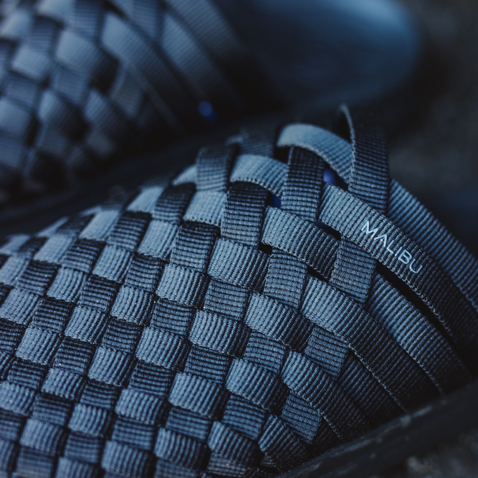 Close-up of dark blue W Colony hand-woven mule sandals by Malibu Sandals, featuring interlaced straps, ergonomic footbed, and visible brand logo on one strap.