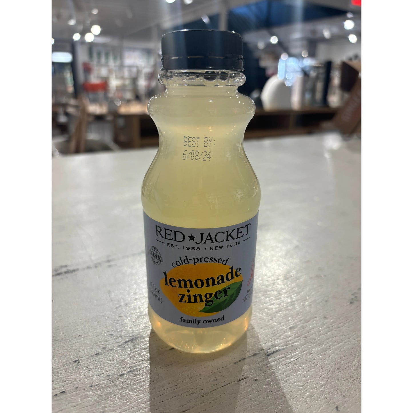 A bottle of Westerlind Cold Pressed Lemonade Zinger on a store shelf, displaying a "best by" date of 6/08/24.