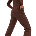 A person in the Isabel Soft Shell Bib Pant by Halfdays, featuring a slim fit and hands in pockets, viewed from the side.