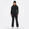 A person wearing a black beanie, black thermal clothing, and slim-fit Isabel Soft Shell Bib Pant by Halfdays stands against a plain white background.