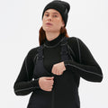 A person zips up the front of their slim-fit black Isabel Soft Shell Bib Pant from Halfdays, standing against a plain background.