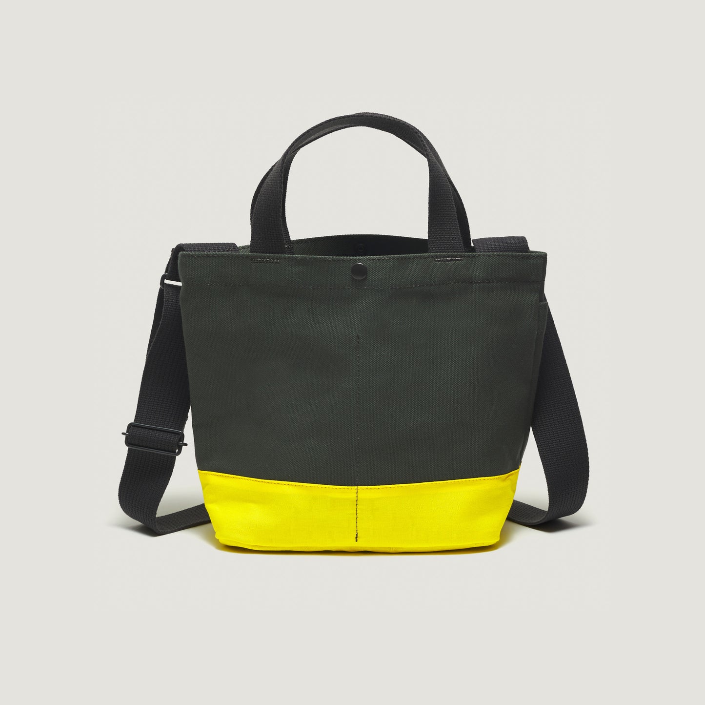 The New York Tote Small, Special Edition: Forest Green/Yellow by Bags in Progress features black handles, an adjustable strap, handy external pockets for extra storage and a forest green design with a bright yellow bottom.