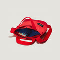 The New York Tote Small, Special Edition: Red/Red by Bags in Progress is a vibrant tote with practical pockets, a blue-lined compartment for books, red handles, and a shoulder strap, blending style and functionality perfectly.