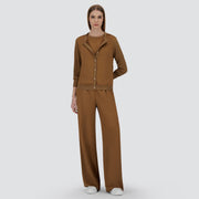 A woman faces forward, wearing the Herno Glam Knit Satin Cardigan in brown with matching wide-leg pants and white sneakers, set against a plain light background.