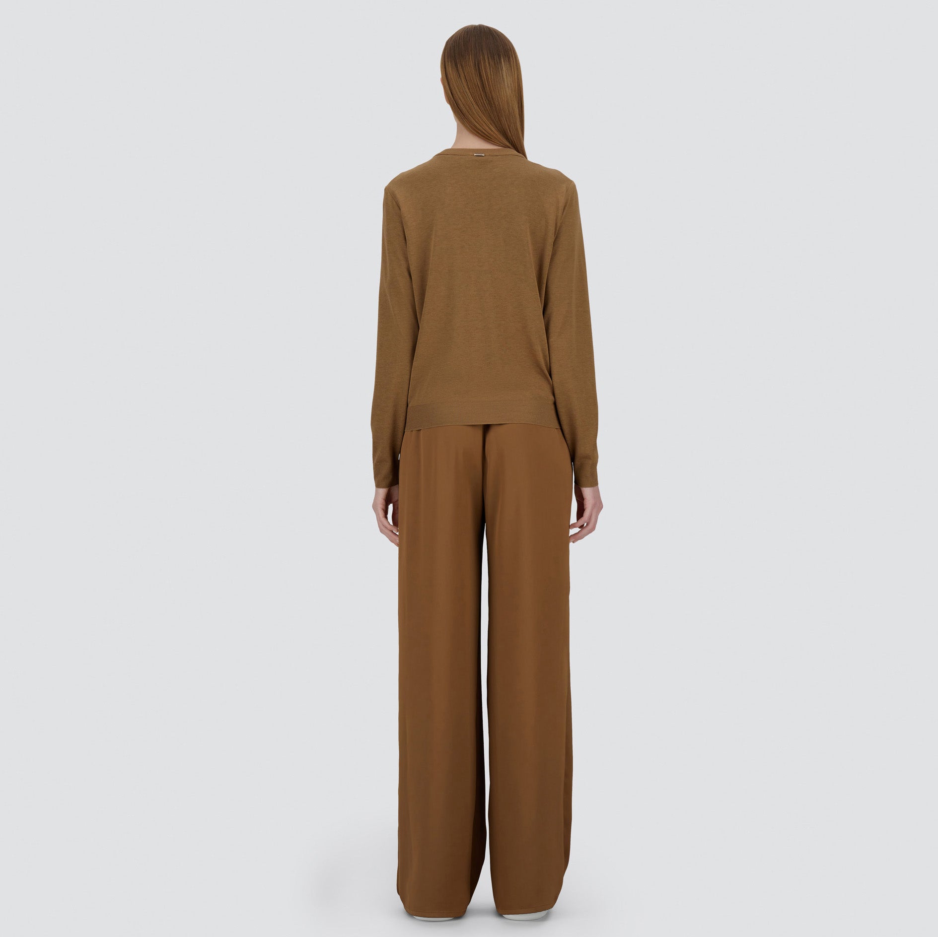 A person stands facing away from the camera wearing the Herno Glam Knit Satin Cardigan against a plain light background.