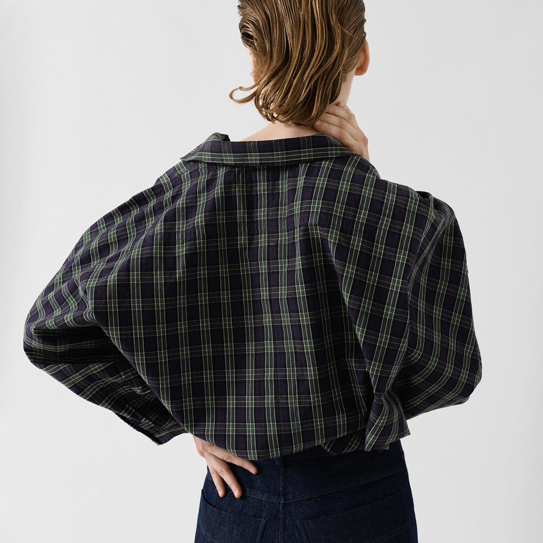 A person with wet, slicked-back hair is seen from behind wearing the Jan Machenhauer Nina Shirt in Purple Check and dark jeans against a plain background.