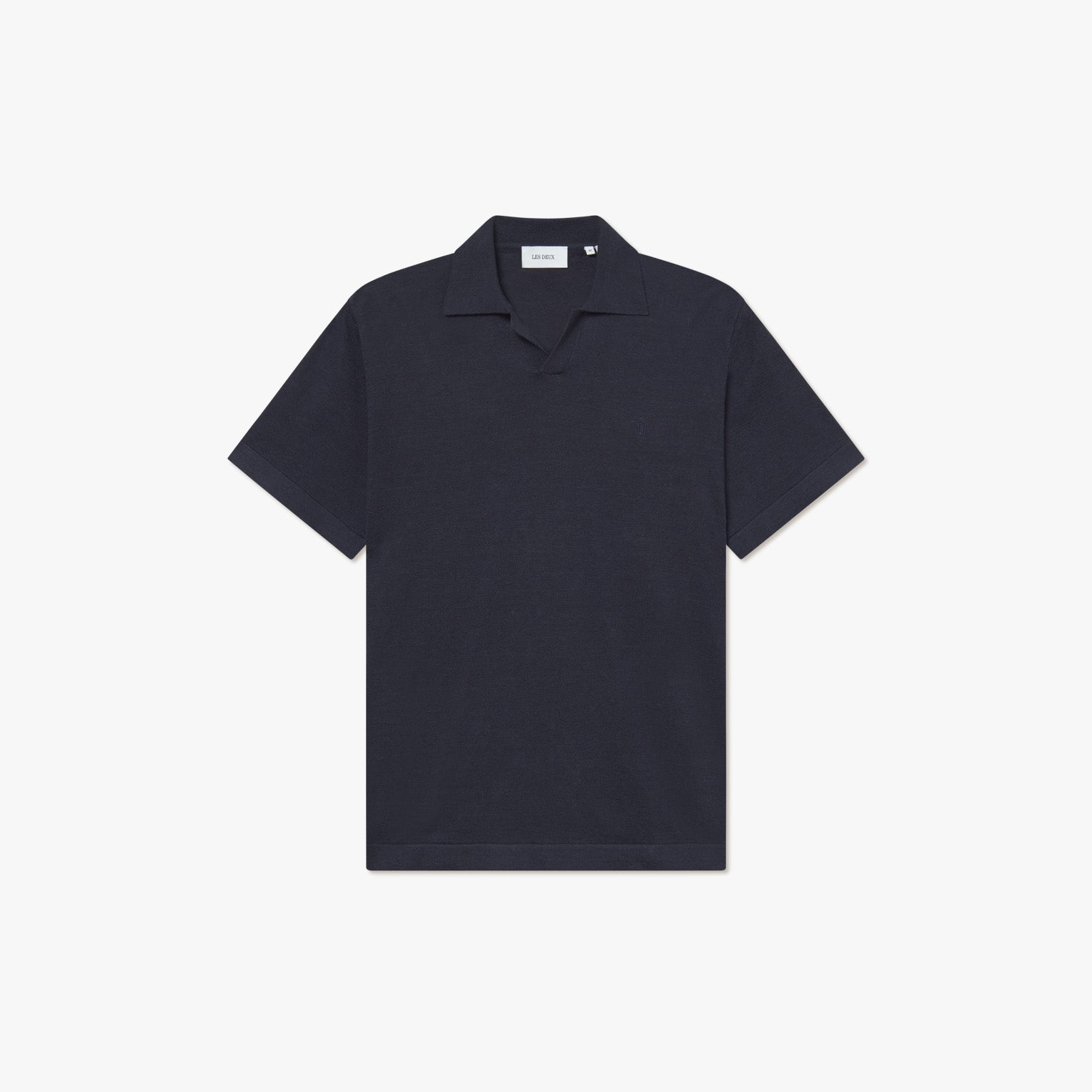 The Les Deux Knit Polo is a plain, short-sleeve, dark navy shirt with a collar and subtle vintage style, shown on a white background.