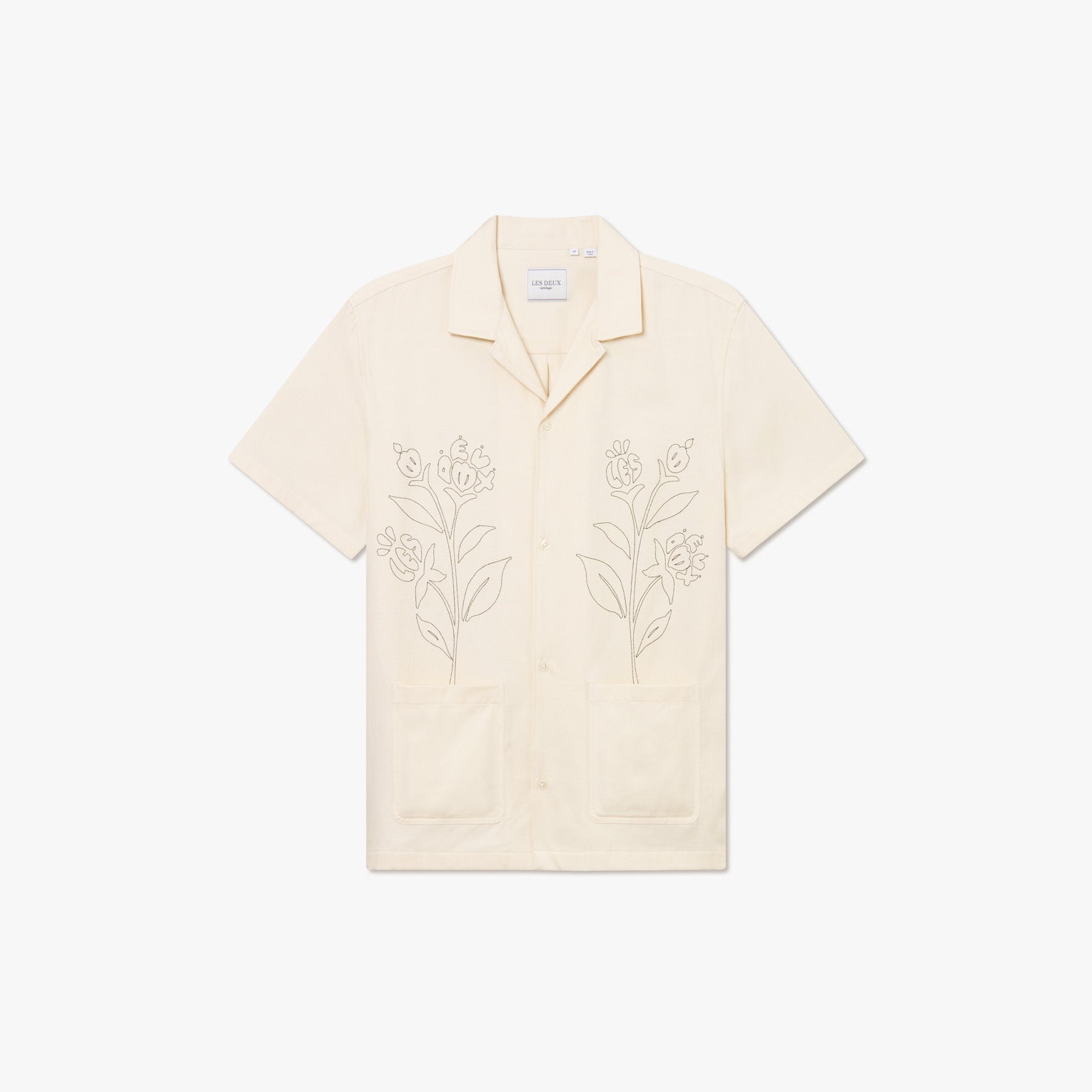 The Kingsley AOE SS Shirt by Les Deux is a short-sleeve, cream button-up in organic cotton with a camp collar, bold front flower embroidery, and two large lower pockets.