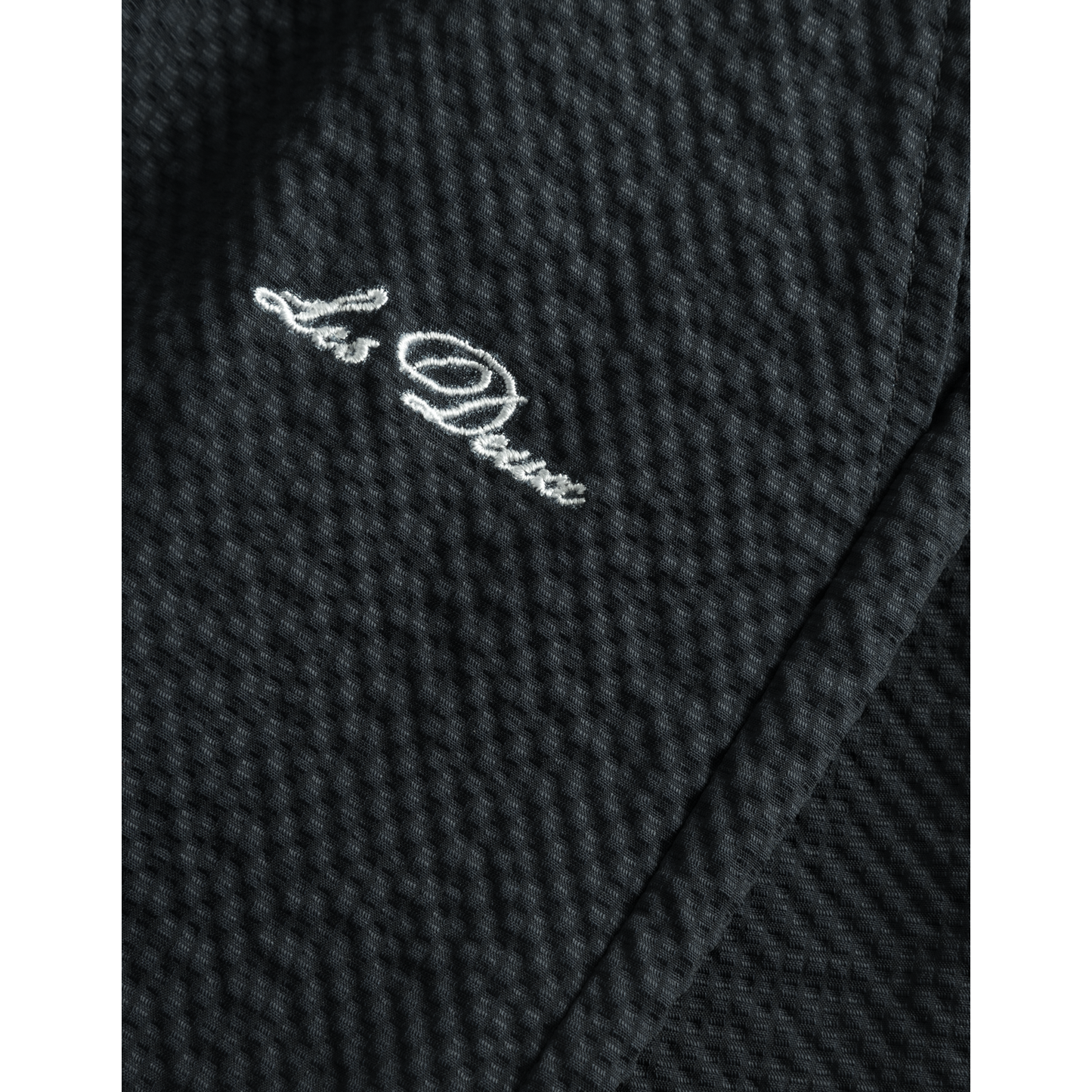 Close-up of a dark, quick-dry Stan Seersucker Swim Shorts 2.0 in Dark Navy with a "la dolce" embroidered inscription in white thread by Les Deux.
