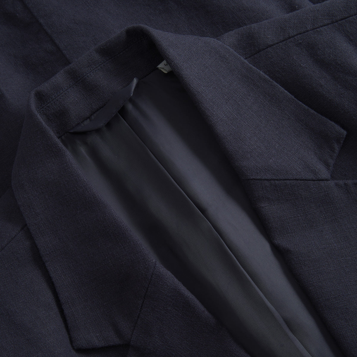 Close-up of the Les Deux James Linen Blazer in dark navy blue, showcasing its loose fit, sharp lapel, collar, and smooth lining—ideal for stylish warm weather suiting.
